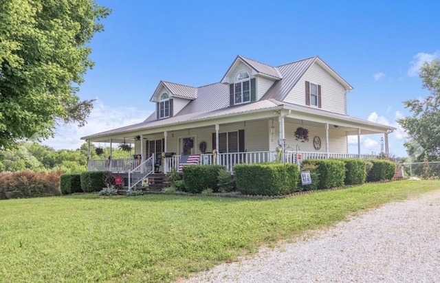 farmhouse-style home with covered porch, metal roof, and a front lawn