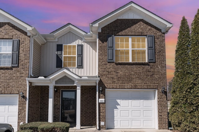 view of front of home featuring an attached garage, board and batten siding, and brick siding