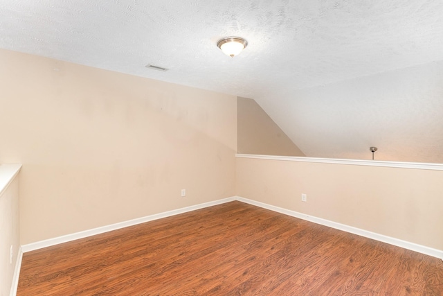 bonus room featuring lofted ceiling, visible vents, a textured ceiling, wood finished floors, and baseboards