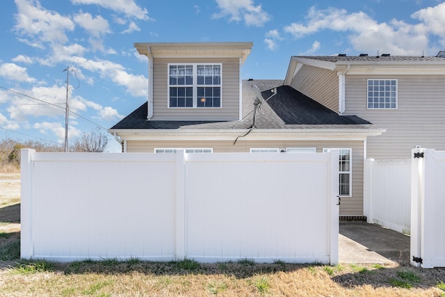 view of home's exterior featuring fence and roof with shingles