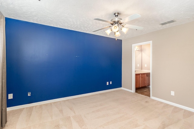 empty room with ceiling fan, a textured ceiling, carpet flooring, visible vents, and baseboards