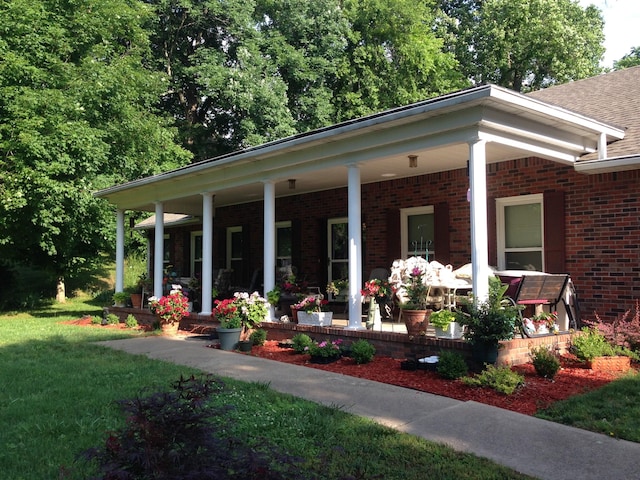 view of front of house with a front lawn, covered porch, and brick siding