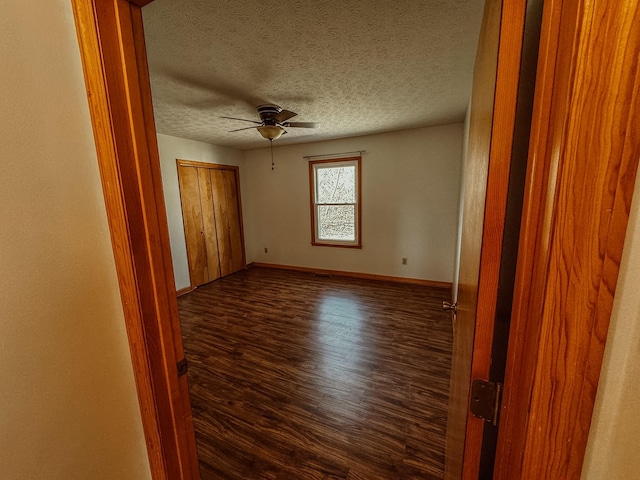 unfurnished room featuring a textured ceiling, baseboards, ceiling fan, and dark wood-style flooring