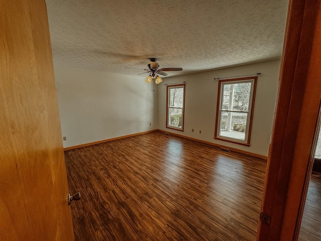 unfurnished room featuring dark wood finished floors, baseboards, and a textured ceiling