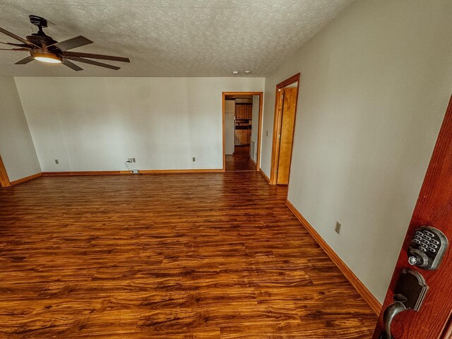 spare room featuring ceiling fan, baseboards, a textured ceiling, and dark wood finished floors