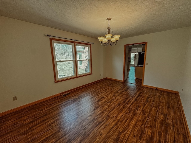 unfurnished room featuring visible vents, a notable chandelier, a textured ceiling, wood finished floors, and baseboards