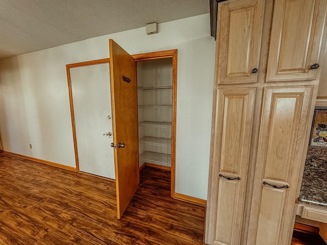 corridor with baseboards, a textured ceiling, and dark wood finished floors