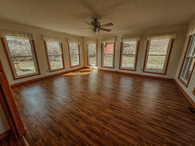 unfurnished sunroom featuring visible vents, a wealth of natural light, and ceiling fan