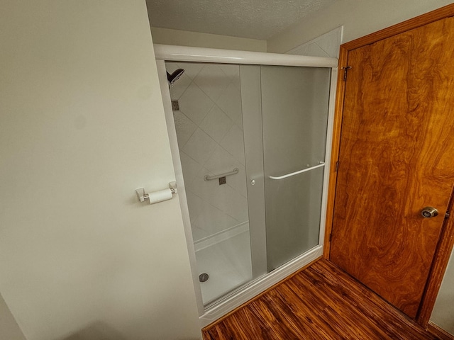 bathroom featuring a stall shower, a textured ceiling, and wood finished floors