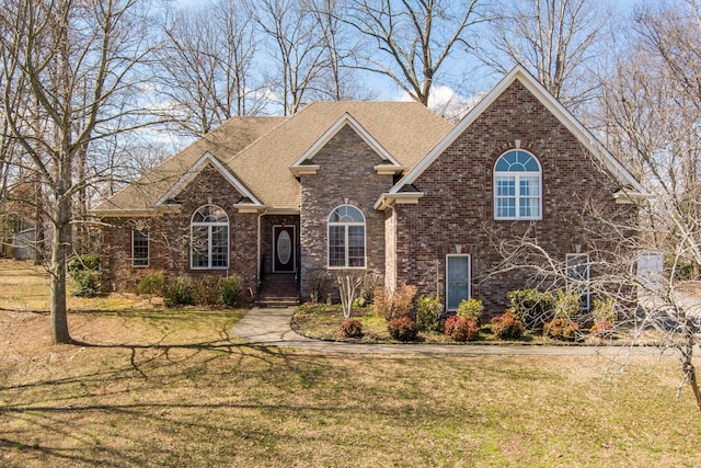 traditional-style house featuring brick siding, a front lawn, and a shingled roof