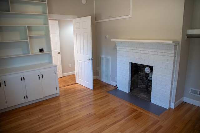 unfurnished living room with light wood-style flooring, a fireplace, and visible vents