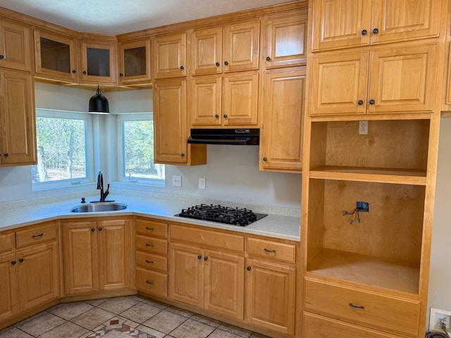 kitchen featuring a sink, under cabinet range hood, black gas cooktop, light countertops, and glass insert cabinets