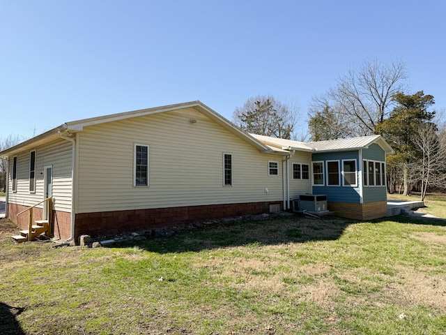 back of house featuring a sunroom, a lawn, and entry steps