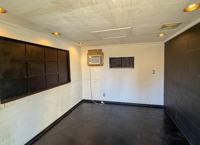 unfurnished room featuring visible vents, a textured ceiling, a wall unit AC, concrete block wall, and attic access