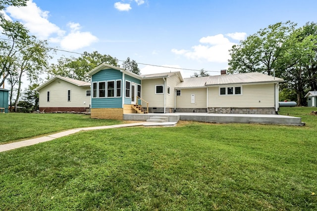 view of front of house featuring metal roof, a sunroom, a front yard, and entry steps