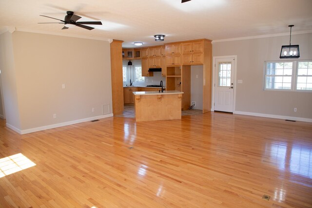 unfurnished living room featuring baseboards, ceiling fan with notable chandelier, light wood-style floors, and ornamental molding