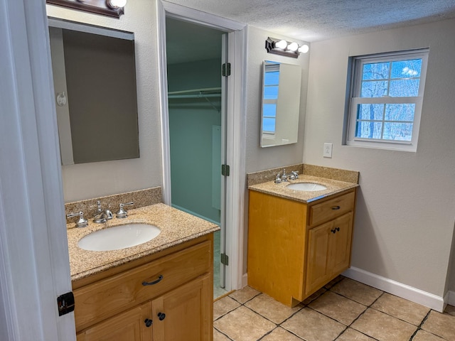 full bathroom featuring a sink, a textured ceiling, two vanities, and tile patterned floors