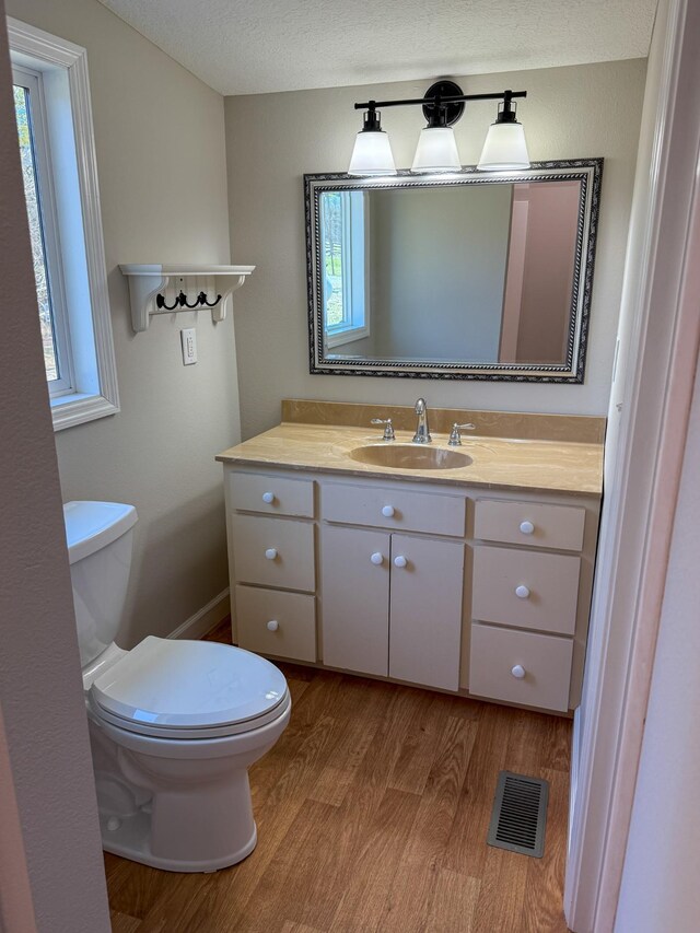 bathroom featuring vanity, wood finished floors, visible vents, a textured ceiling, and toilet