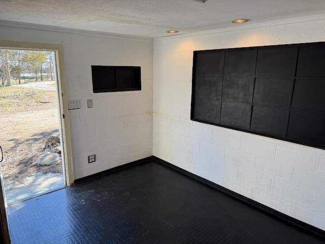 unfurnished room with recessed lighting, a textured ceiling, and concrete block wall