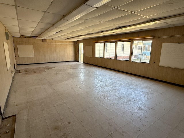 spare room with wooden walls, a paneled ceiling, and light floors