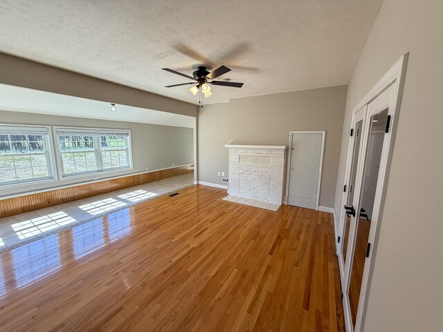 interior space with visible vents, a ceiling fan, a textured ceiling, light wood-style floors, and baseboards