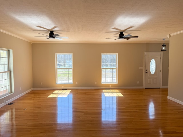 unfurnished living room with visible vents, baseboards, ornamental molding, wood finished floors, and a textured ceiling