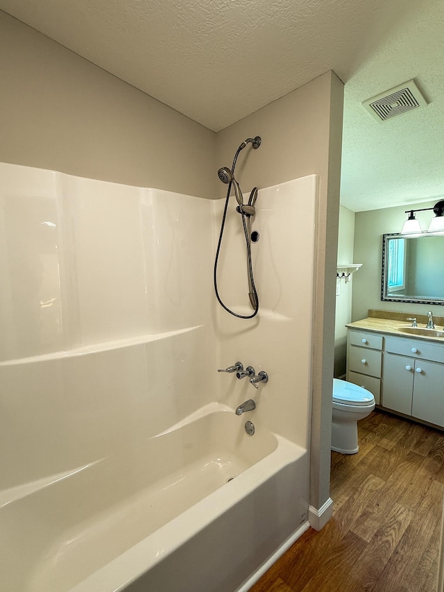 full bath with visible vents, toilet, a textured ceiling, wood finished floors, and vanity