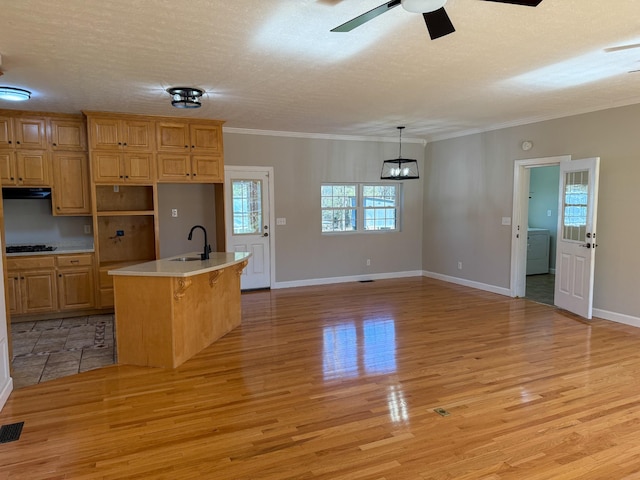 kitchen featuring ornamental molding, black gas stovetop, light wood-style floors, and a sink