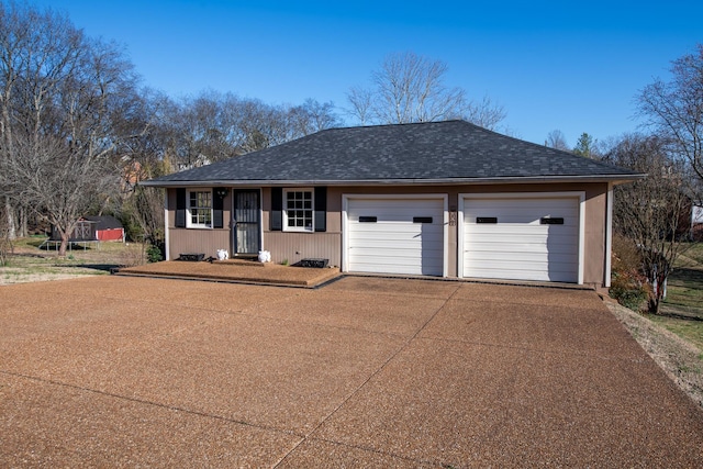 ranch-style home with a garage, roof with shingles, and concrete driveway