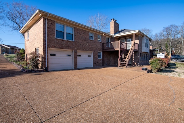 back of property featuring stairway, concrete driveway, an attached garage, brick siding, and a chimney