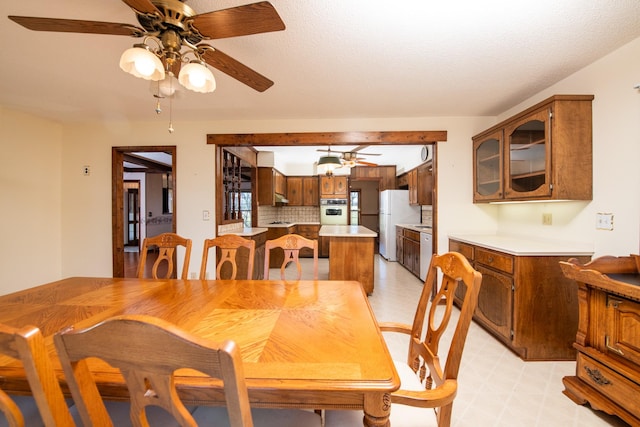 dining space featuring a ceiling fan, light floors, and a textured ceiling