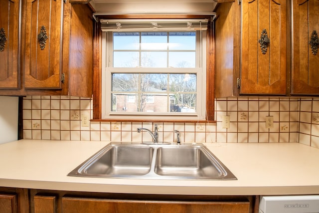 kitchen featuring brown cabinetry, tasteful backsplash, light countertops, and a sink