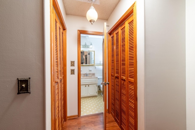 corridor featuring light wood-type flooring and a sink