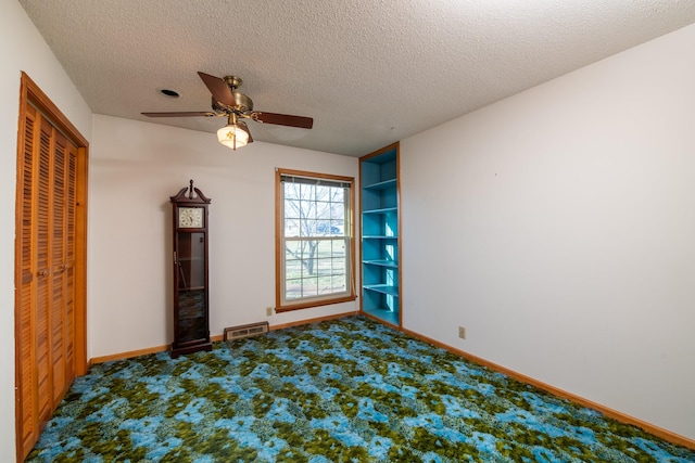 carpeted empty room featuring a textured ceiling, baseboards, and ceiling fan