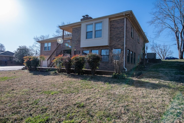 rear view of property with stairs, a yard, brick siding, and a chimney