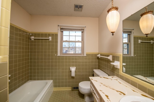 full bathroom featuring tile patterned floors, visible vents, toilet, a textured ceiling, and tile walls