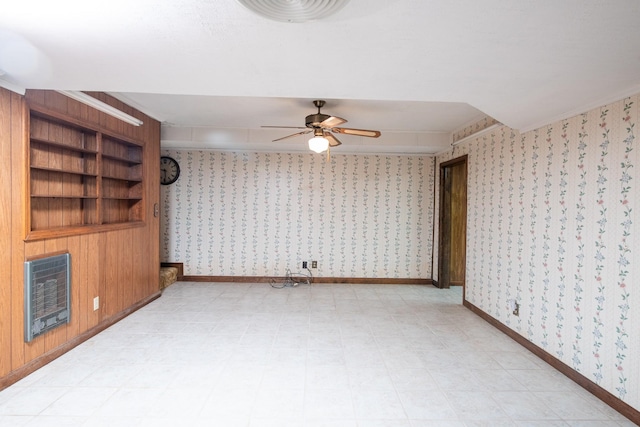 empty room with wallpapered walls, heating unit, baseboards, and ceiling fan