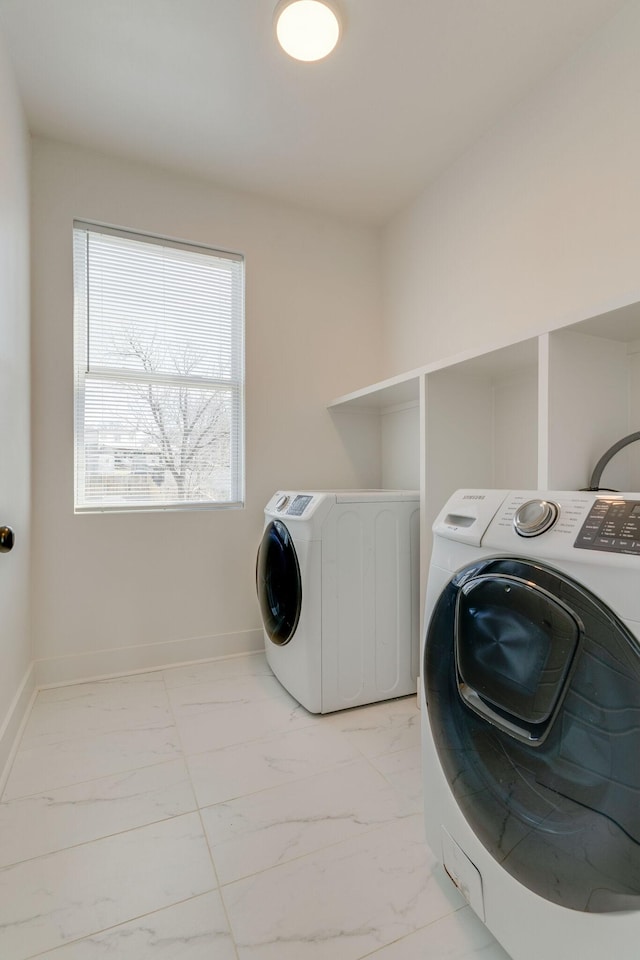 laundry room featuring marble finish floor, washing machine and clothes dryer, baseboards, and laundry area