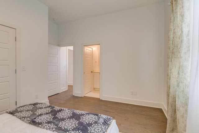 bedroom featuring connected bathroom, baseboards, and wood finished floors