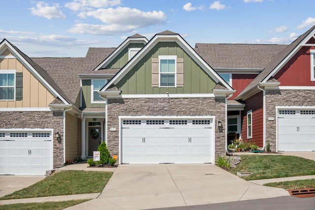 craftsman inspired home with a garage, concrete driveway, stone siding, roof with shingles, and board and batten siding