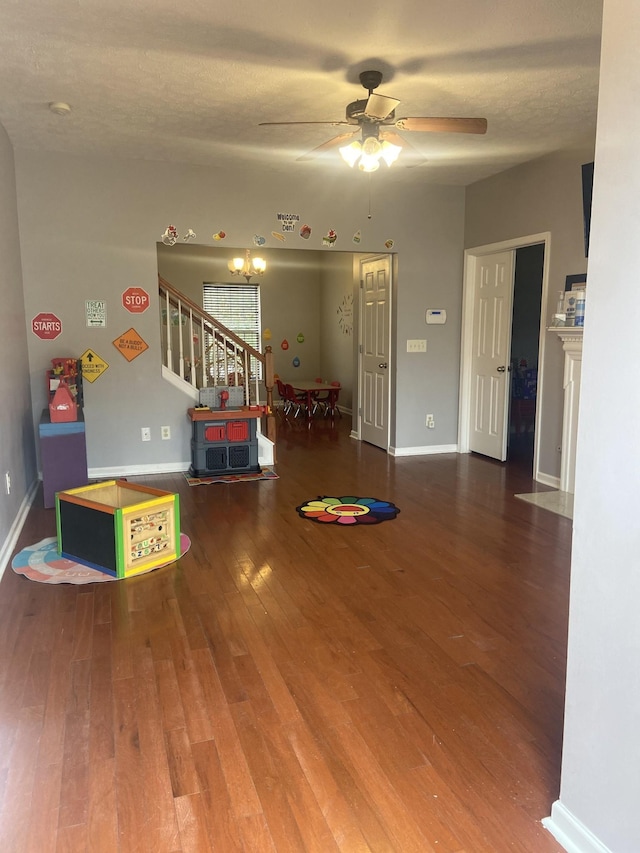 game room with ceiling fan, hardwood / wood-style floors, a textured ceiling, and baseboards