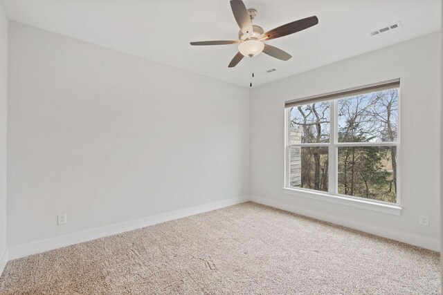 carpeted empty room with visible vents, baseboards, and ceiling fan