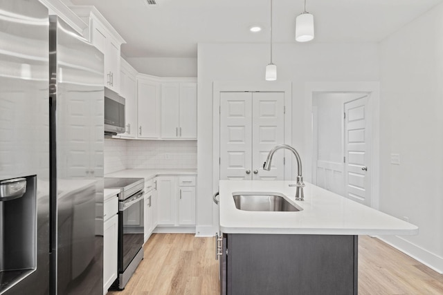 kitchen featuring stainless steel appliances, light countertops, backsplash, white cabinetry, and a sink