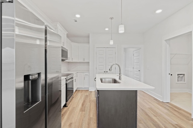 kitchen with stainless steel appliances, a sink, light countertops, and white cabinets