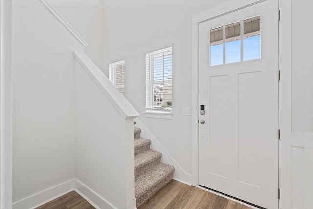 foyer entrance featuring stairs, baseboards, and wood finished floors