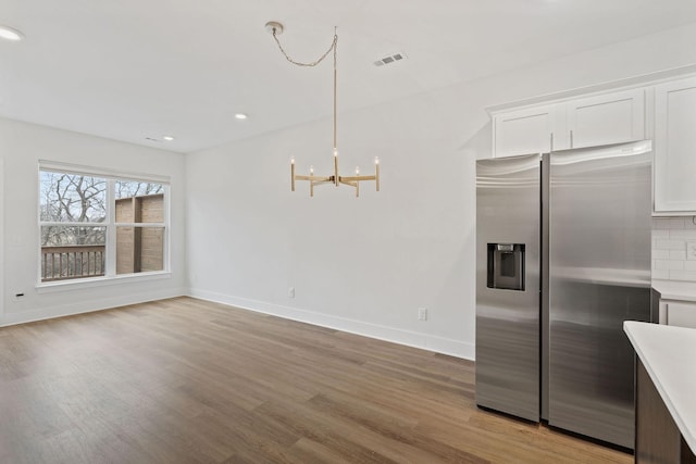 kitchen featuring stainless steel refrigerator with ice dispenser, backsplash, visible vents, and light wood-style floors