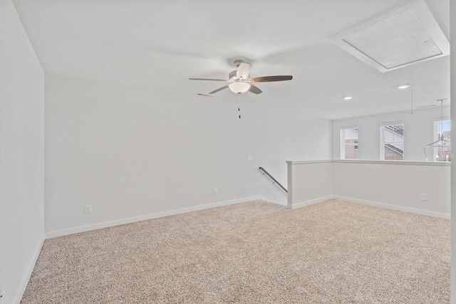 spare room with attic access, carpet flooring, ceiling fan, and baseboards