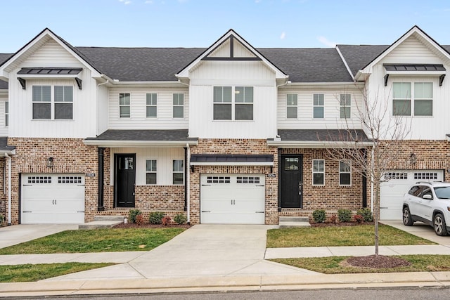 townhome / multi-family property featuring board and batten siding, concrete driveway, brick siding, and a shingled roof