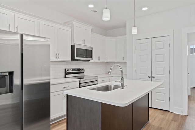 kitchen featuring stainless steel appliances, light countertops, light wood-style floors, white cabinetry, and a sink