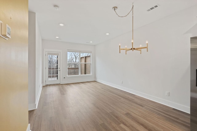 unfurnished dining area featuring wood finished floors, visible vents, and baseboards